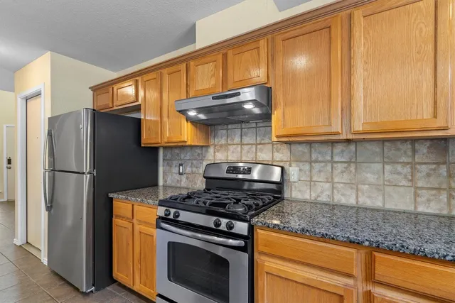 a kitchen with stainless steel appliances granite countertop a refrigerator stove and microwave