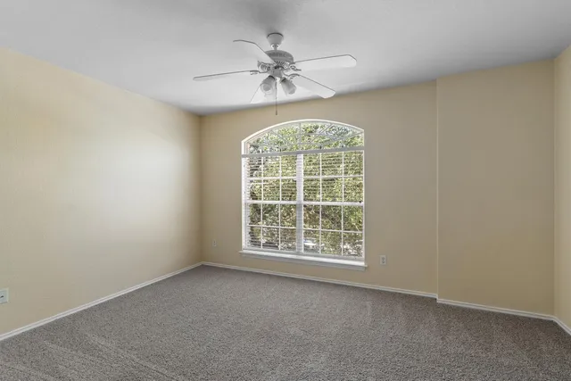 an empty room with a window and a fan