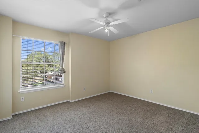 a view of an empty room with chandelier fan and fire place