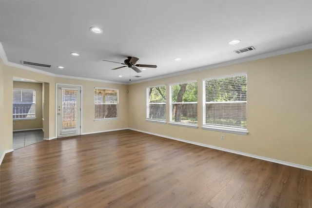 a view of an empty room with wooden floor and a window