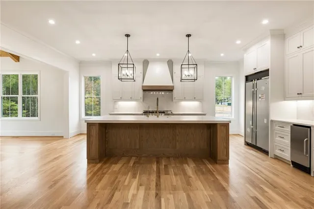 a large kitchen with stainless steel appliances granite countertop a stove a sink dishwasher a refrigerator and a wooden floor