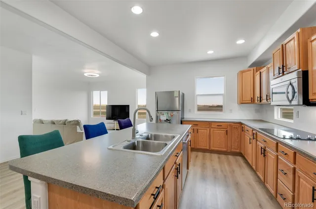 a kitchen with stainless steel appliances granite countertop a sink dishwasher a stove top oven a refrigerator with island and chairs