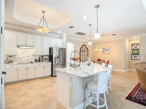 a kitchen with stainless steel appliances kitchen island granite countertop a sink a stove a refrigerator cabinets and chairs