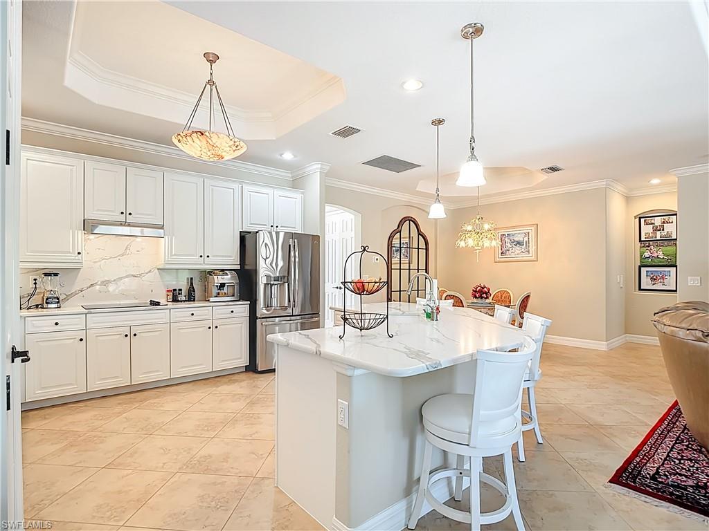9250 Veneto Place Naples, FL 34113 - Photo 23 of 50 a kitchen with stainless steel appliances kitchen island granite countertop a sink a stove a refrigerator cabinets and chairs
