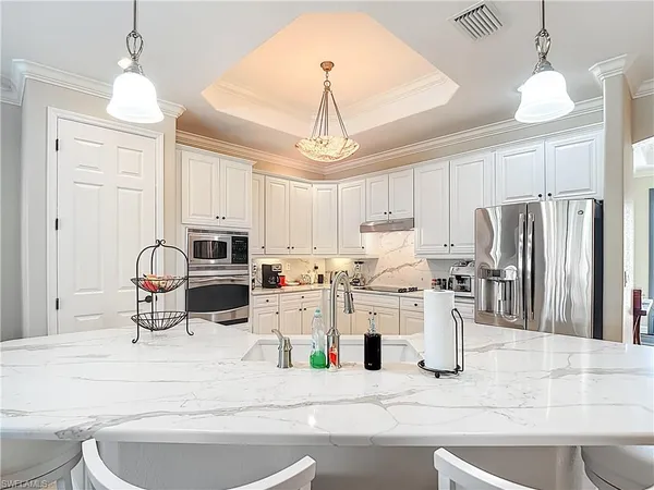 a kitchen with stainless steel appliances kitchen island granite countertop a refrigerator a stove a sink dishwasher a dining table and chairs with wooden floor