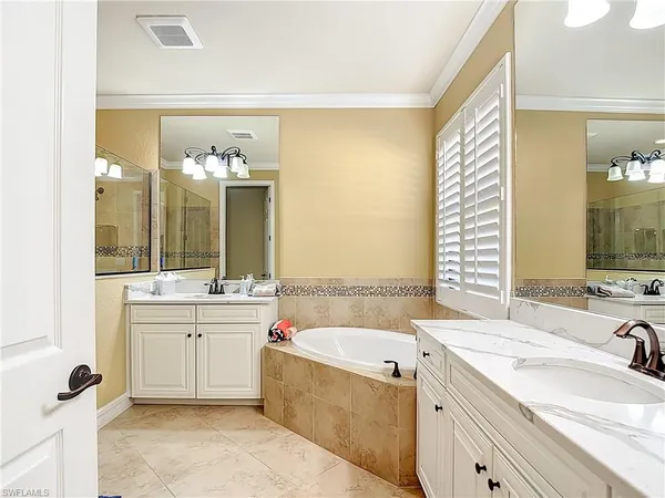 a bathroom with a granite countertop double vanity sink a mirror and a bathtub