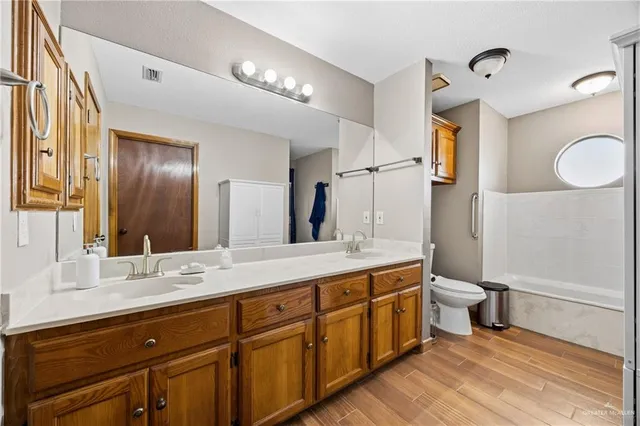 a spacious bathroom with a double vanity sink a toilet and a mirror