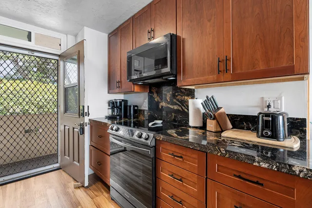 a kitchen with stainless steel appliances granite countertop a stove a sink and a microwave