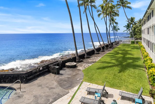 a view of a backyard with lawn chairs under an umbrella