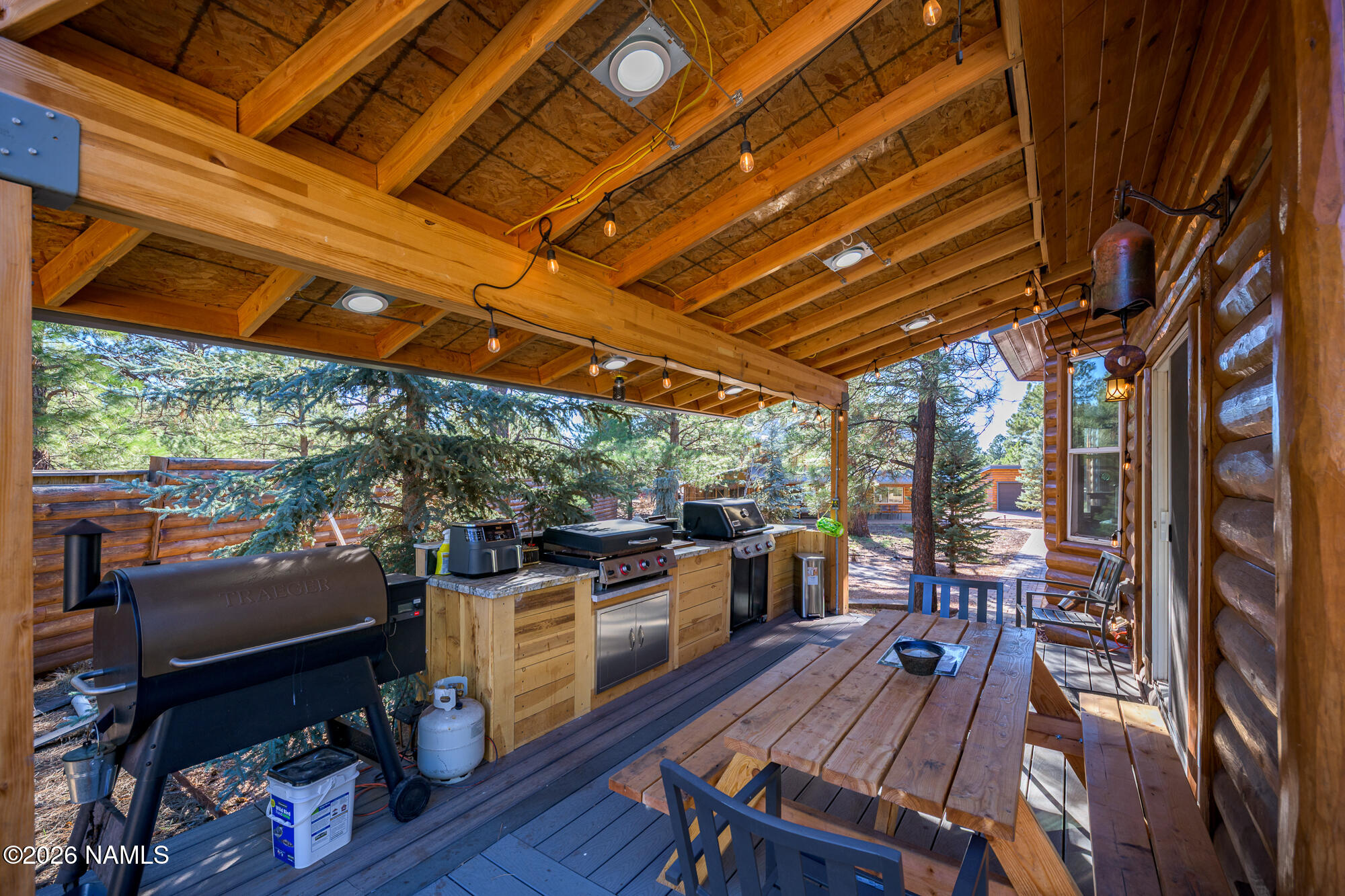 7042 East Robin Hood Road Williams, AZ 86046 - Photo 28 of 58 a view of a patio with table and chairs a barbeque with wooden floor and roof with barbeque grill