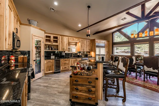 a kitchen with stainless steel appliances kitchen island granite countertop a table chairs refrigerator and microwave