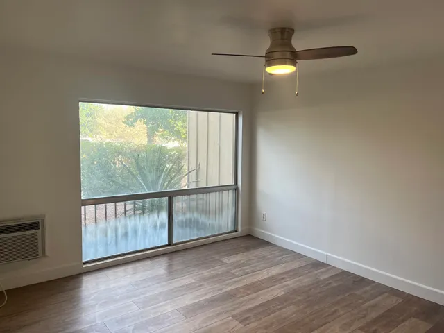an empty room with wooden floor cabinet and windows