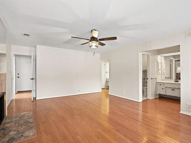 an empty room with wooden floor and a ceiling fan