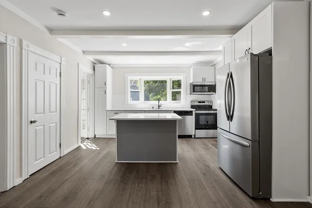 a kitchen with kitchen island a counter top space a sink and stainless steel appliances
