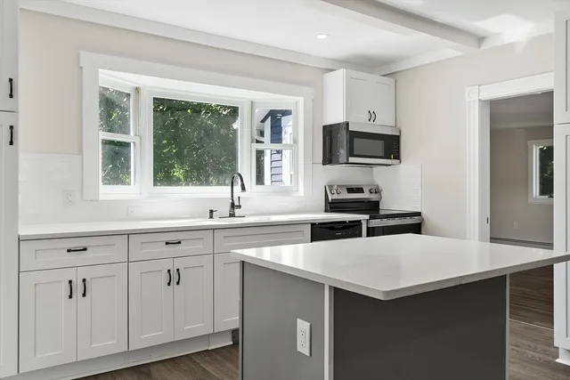 a kitchen with white cabinets and sink