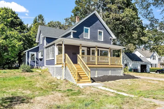 a view of a house with a yard and large tree