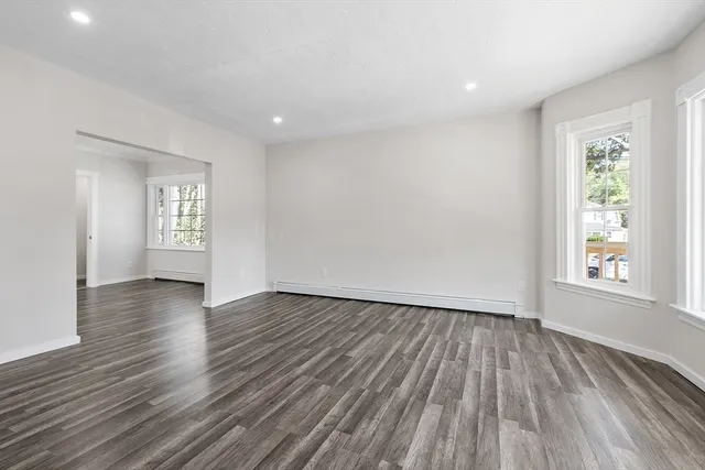 an empty room with wooden floor and window