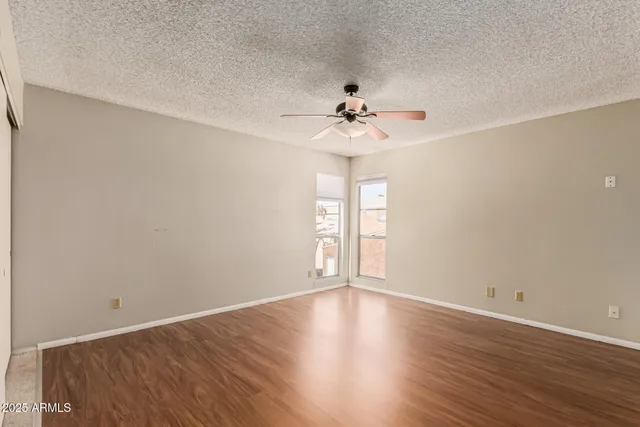 an empty room with wooden floor and a ceiling fan