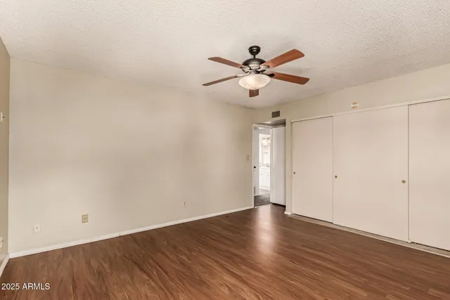 a view of empty room with wooden floor and fan
