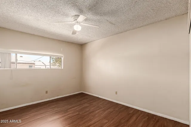 an empty room with wooden floor and a ceiling fan