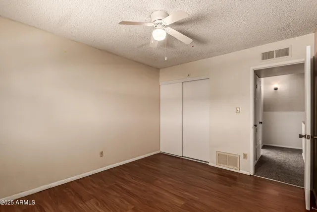 an empty room with wooden floor chandelier fan and windows
