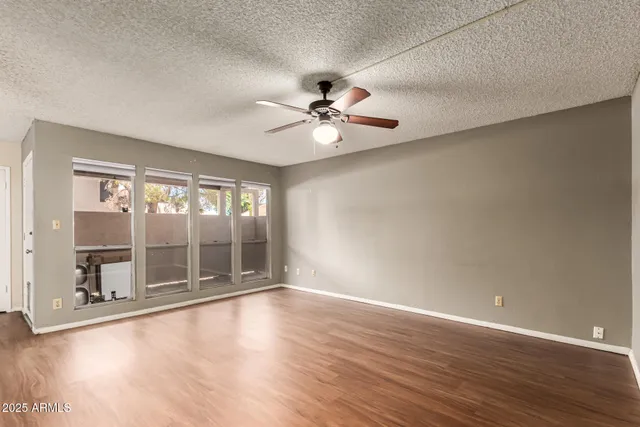 a view of an empty room with a window and wooden floor