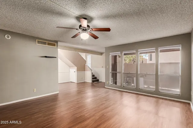 a view of an empty room with a window and wooden floor