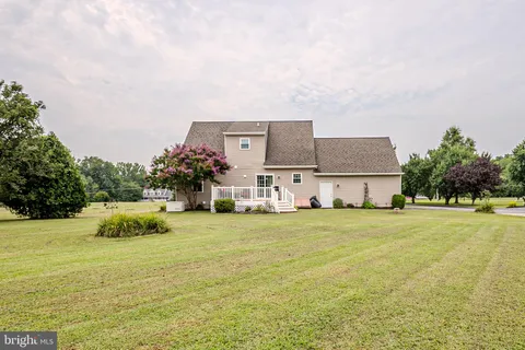 a front view of a house with a garden and lake view