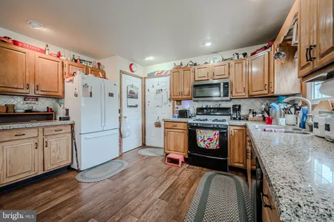 a kitchen with granite countertop a refrigerator a stove top oven a sink and cabinets