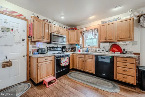 a kitchen with granite countertop a sink cabinets stainless steel appliances and a window