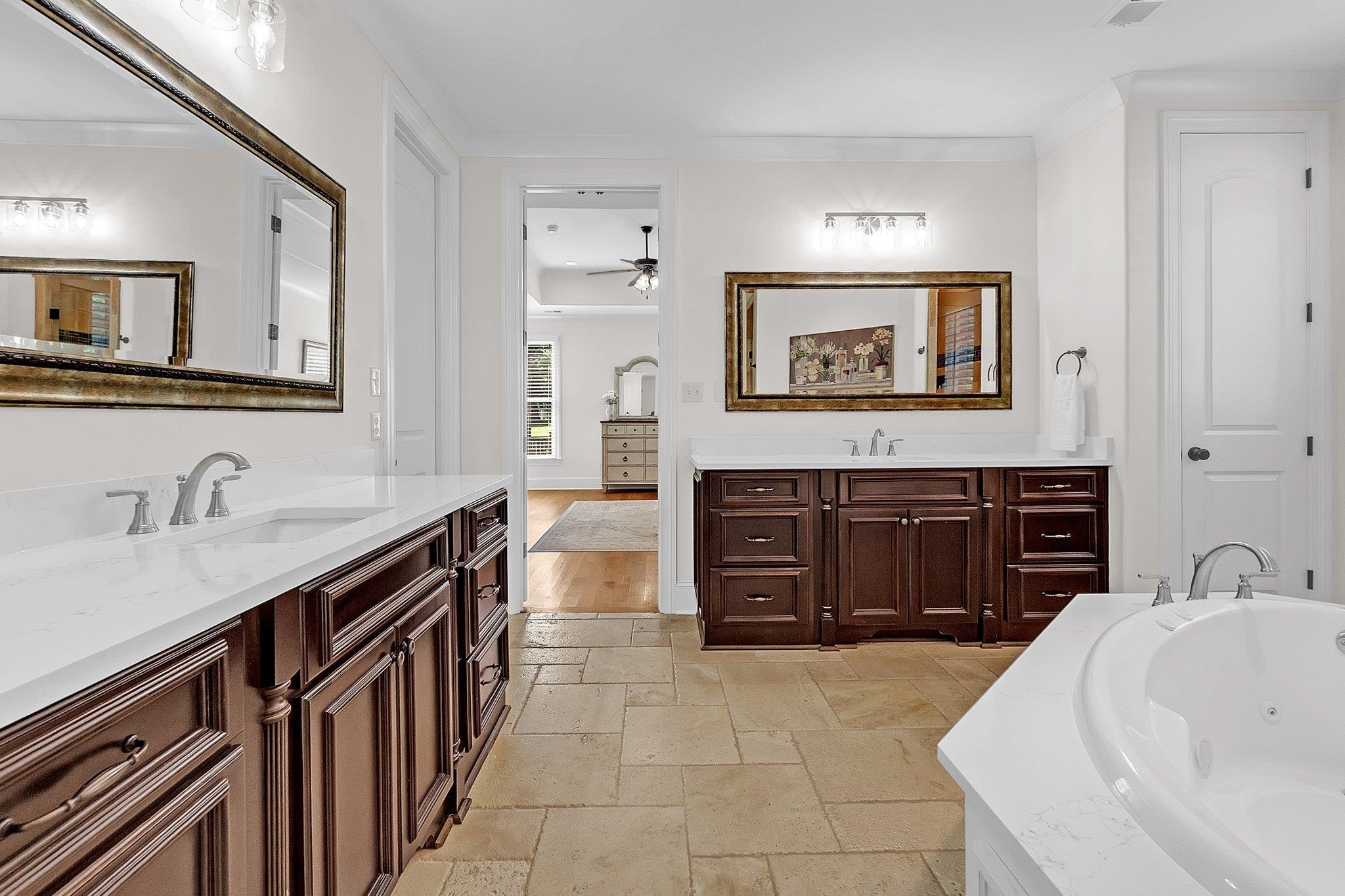 3246 North Hartwell Ridge Drive Collierville, TN 38017 - Photo 25 of 40 Dual vanity with white countertops and dark wood cabinetry, complemented by a large jetted soaking tub