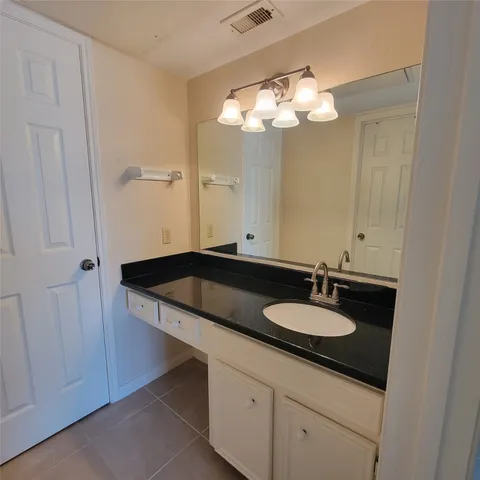 a bathroom with a granite countertop sink a light fixture and a stove