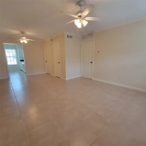 an empty room with chandelier fan and windows
