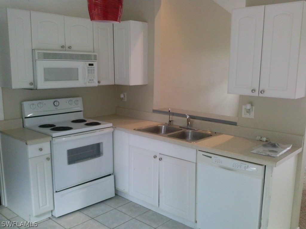 9099 Henry Road Fort Myers, FL 33967 - Photo 4 of 10 a kitchen with white cabinets sink and white appliances