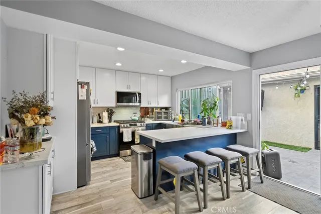 a kitchen with microwave a refrigerator and chairs