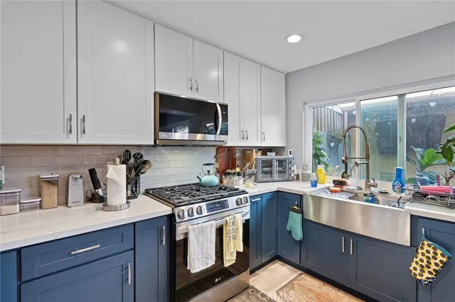 a kitchen with stainless steel appliances granite countertop a sink a stove a microwave a refrigerator and cabinets