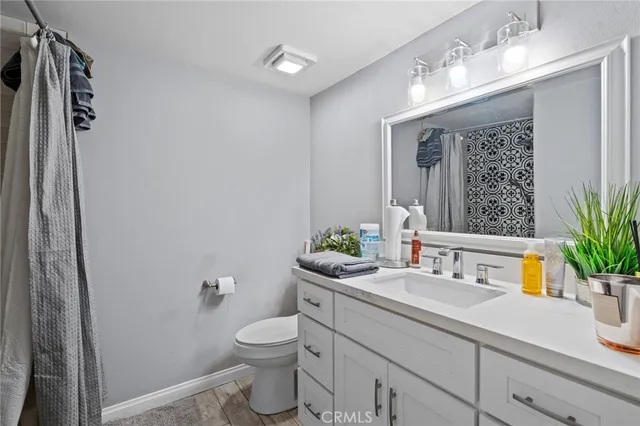 a bathroom with a granite countertop sink a large mirror a toilet and a shower