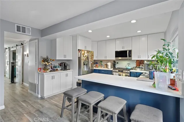a kitchen with a dining table chairs refrigerator and microwave