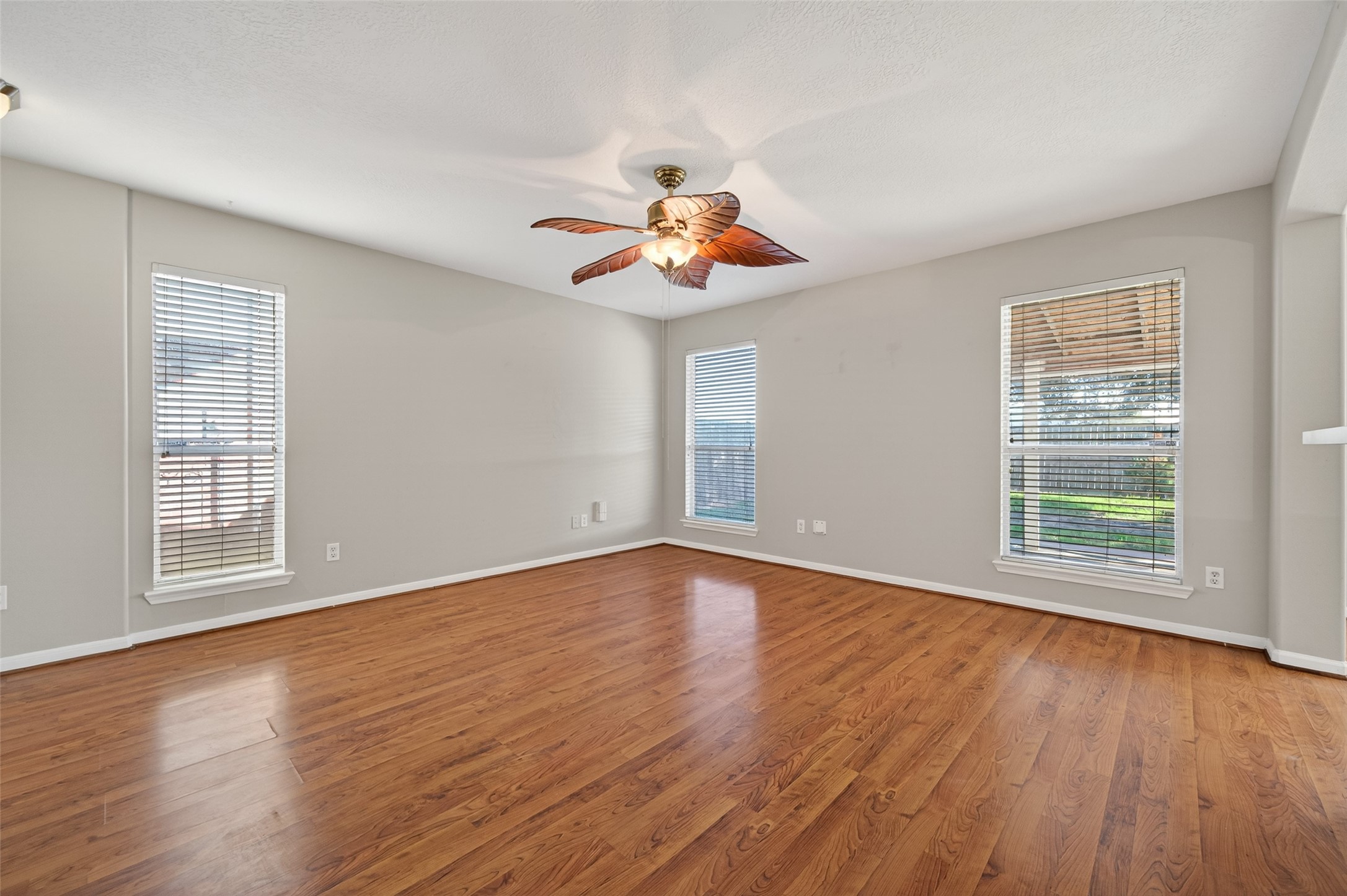 20347 Hunterclif Lane Katy, TX 77449 - Photo 11 of 39 Expansive room featuring warm wood-look flooring, a decorative ceiling fan, and multiple large windows allowing for abundant natural light.