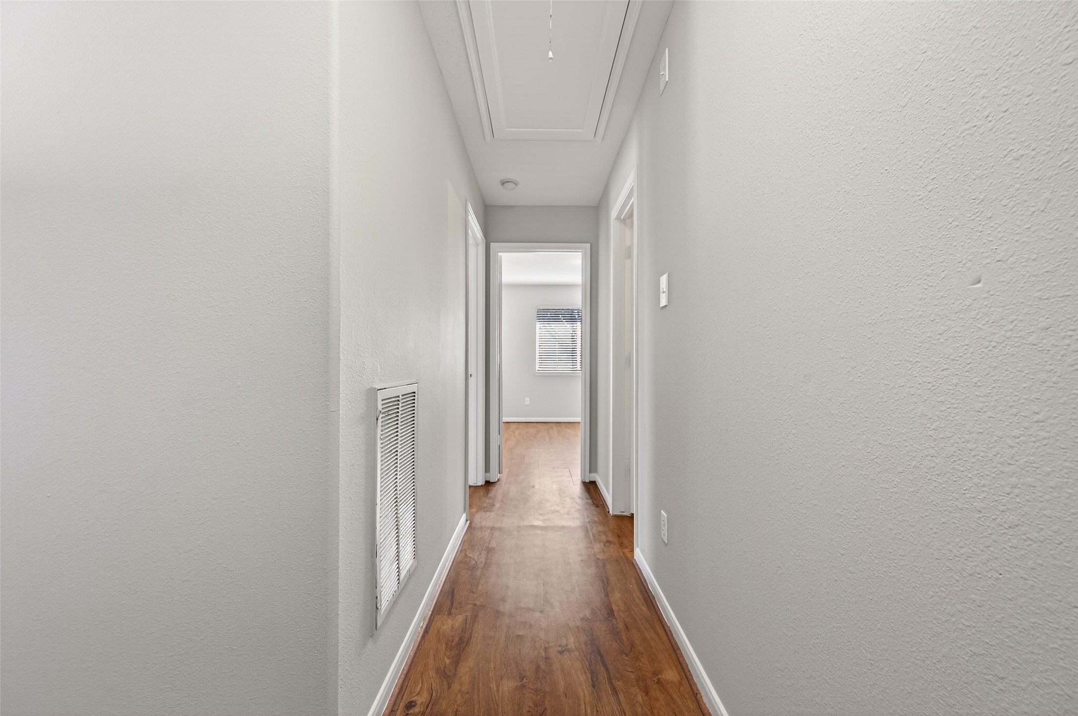 20347 Hunterclif Lane Katy, TX 77449 - Photo 21 of 39 Central hallway featuring attic access, smooth wood-look flooring, and easy flow to the bedrooms and bath.