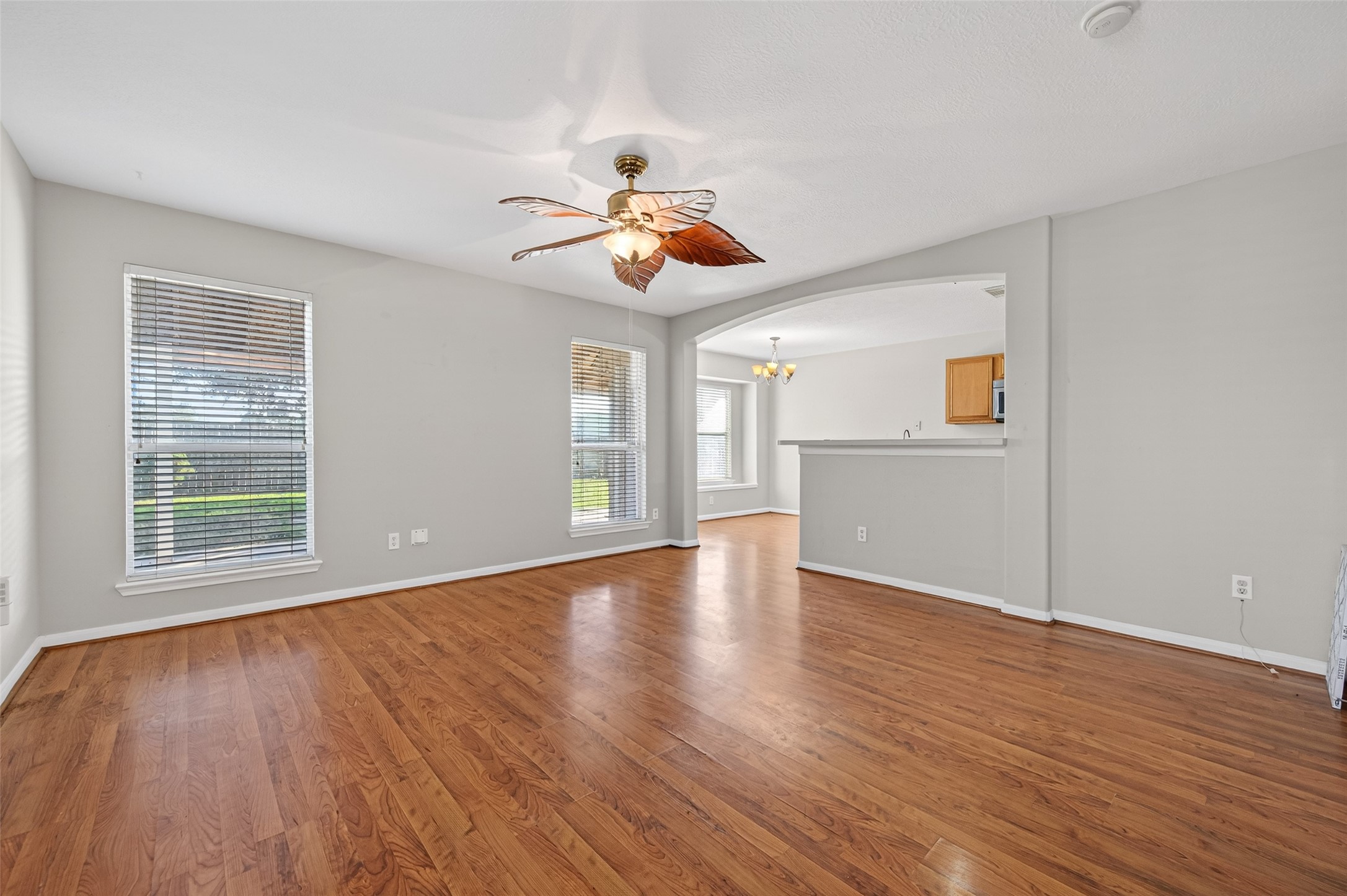 20347 Hunterclif Lane Katy, TX 77449 - Photo 8 of 39 Light-filled living area highlighted by large windows with blinds, wood-style flooring, and an open pass-through view to the kitchen.