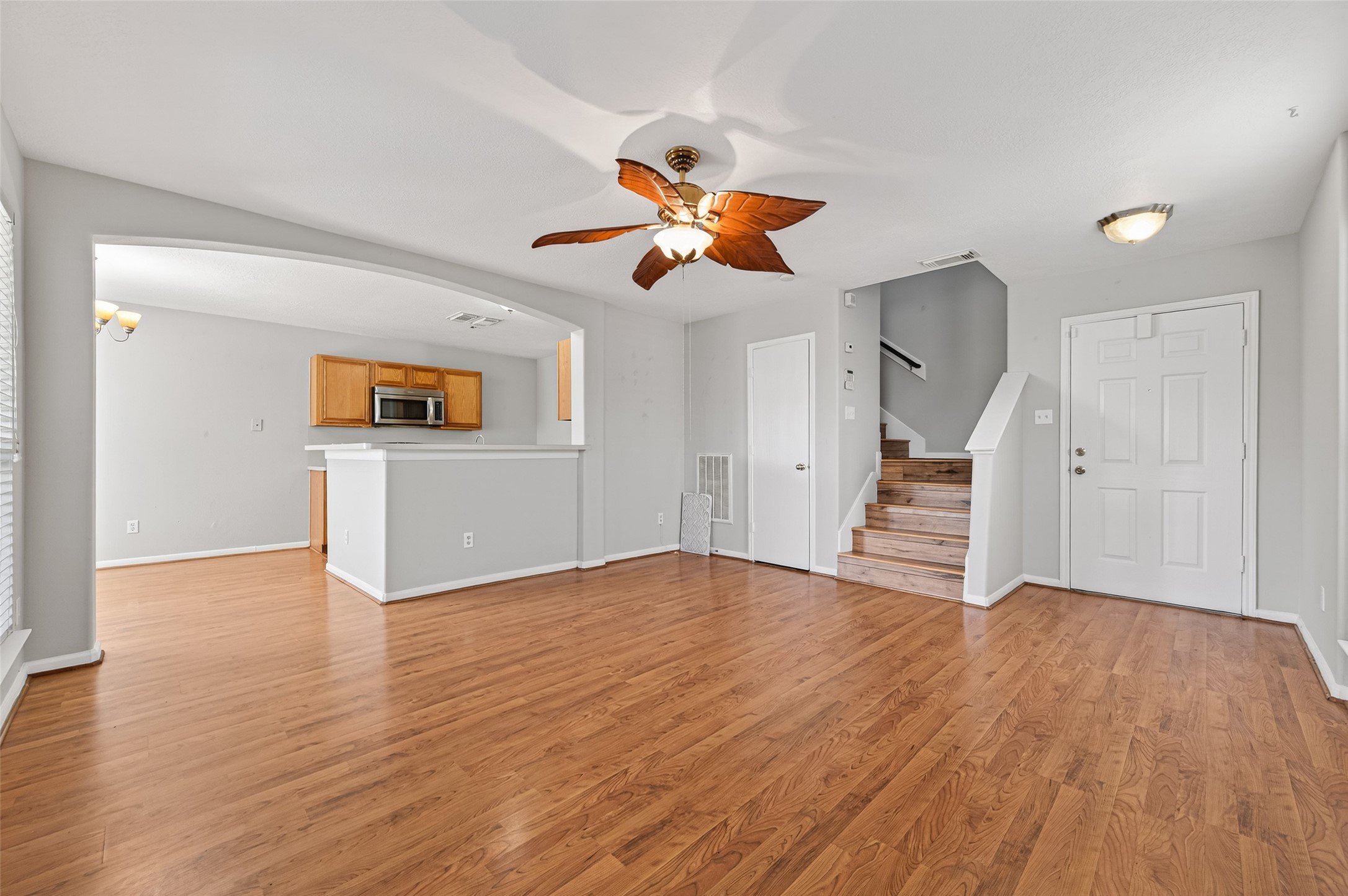20347 Hunterclif Lane Katy, TX 77449 - Photo 10 of 39 Spacious family room featuring a decorative ceiling fan, an arched breakfast bar opening, and seamless wood-look flooring.