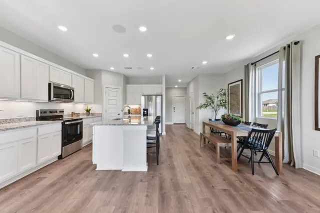 a kitchen with a table chairs microwave and cabinets