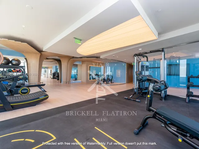 a view of a room with gym equipment and large windows