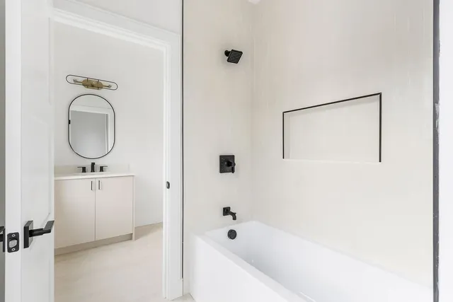 a bathroom with a bathtub a mirror a sink and a vanity