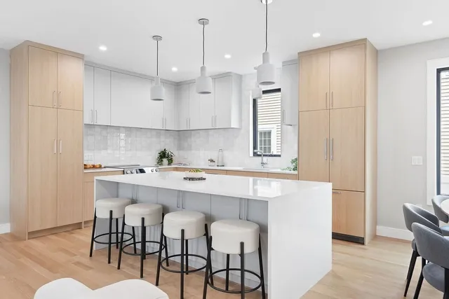 a kitchen with stainless steel appliances granite countertop a sink a stove a refrigerator and island with wooden floor