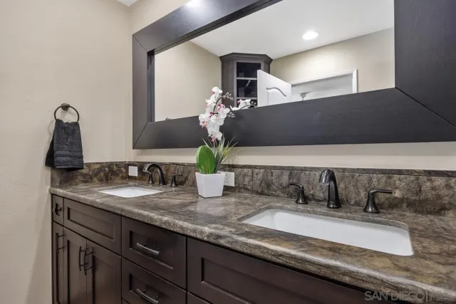 a bathroom with a granite countertop sink a toilet and shower