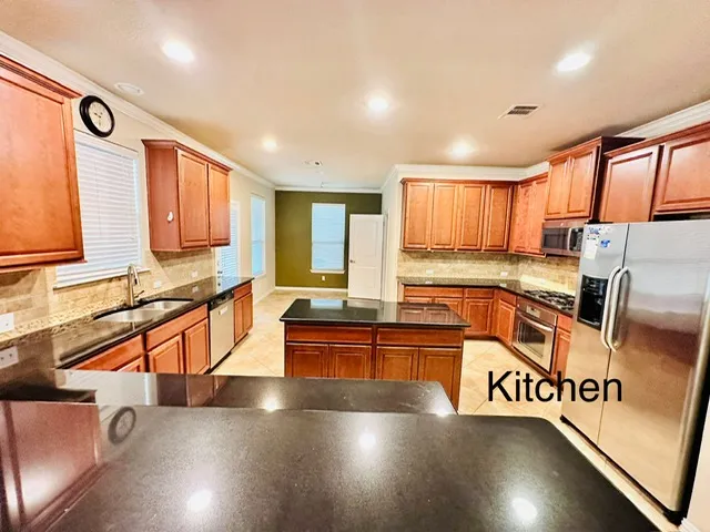 a view of a kitchen with stainless steel appliances granite countertop a stove a sink and a microwave