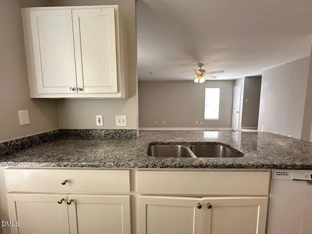 a kitchen with granite countertop a sink and white cabinets