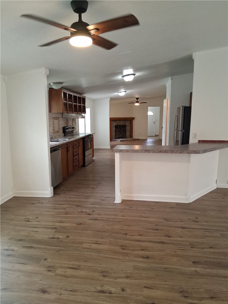 910 Sands Road Cave Springs, AR 72718 - Photo 3 of 11 Wood-finish flooring throughout, stainless steel appliances, kitchen island with breakfast bar, ceiling fans, and a fireplace